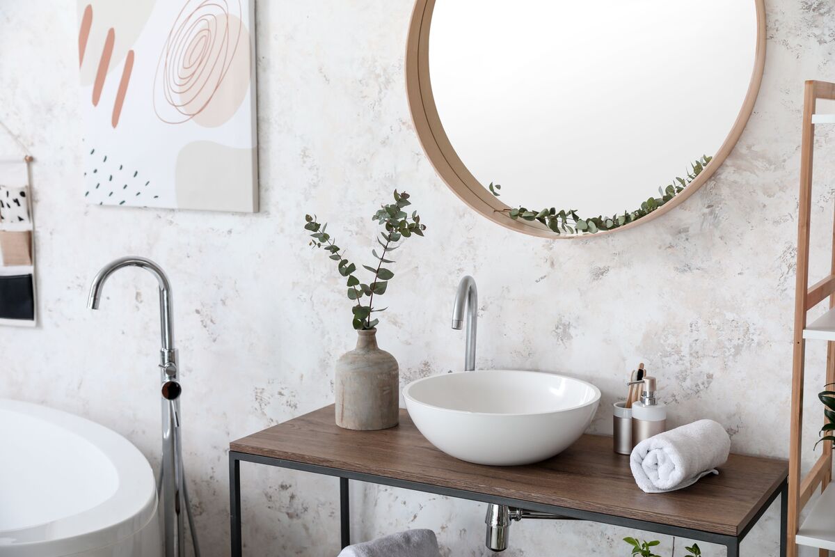 Banheiro com espelho redondo com moldura de madeira