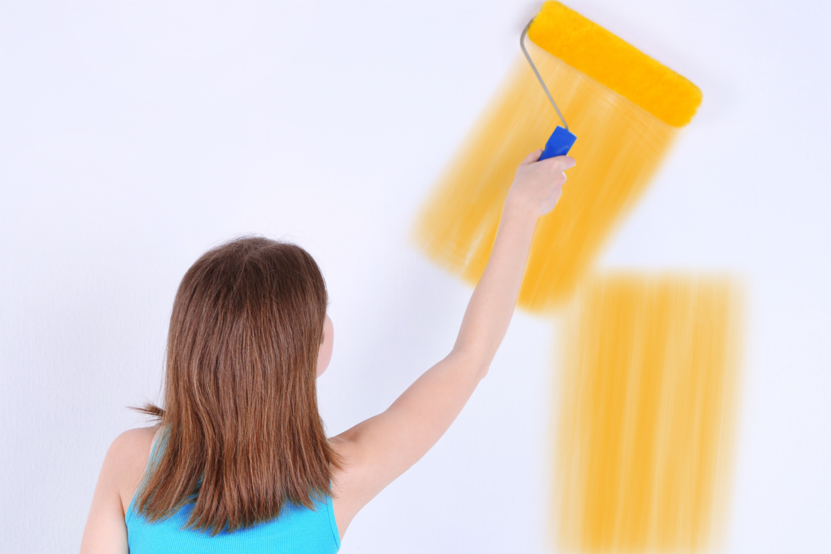 Jovem pintando uma parede de amarelo