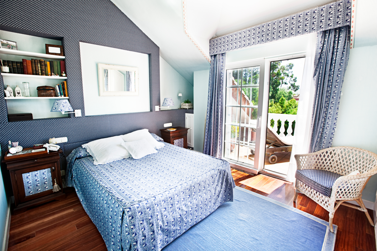 Um quarto com paredes, cortinas e roupa de cama azuis 