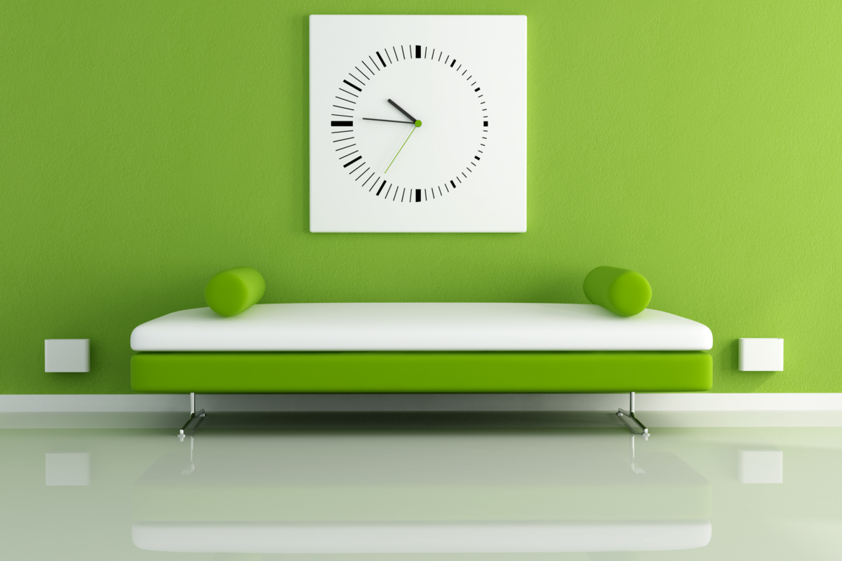 Uma sala com a parede verde, um sofá verde e branco encostado e um relógio branco