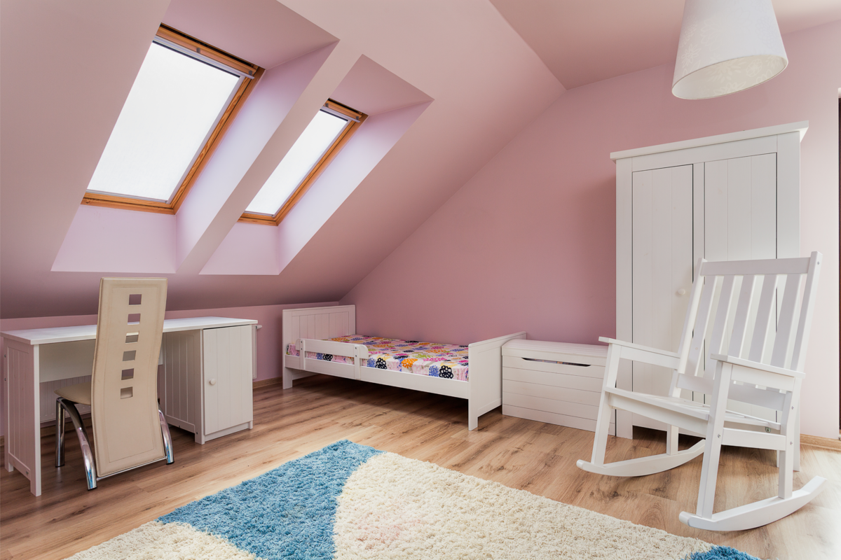 Um pequeno quarto com as paredes rosas claro e móveis brancos