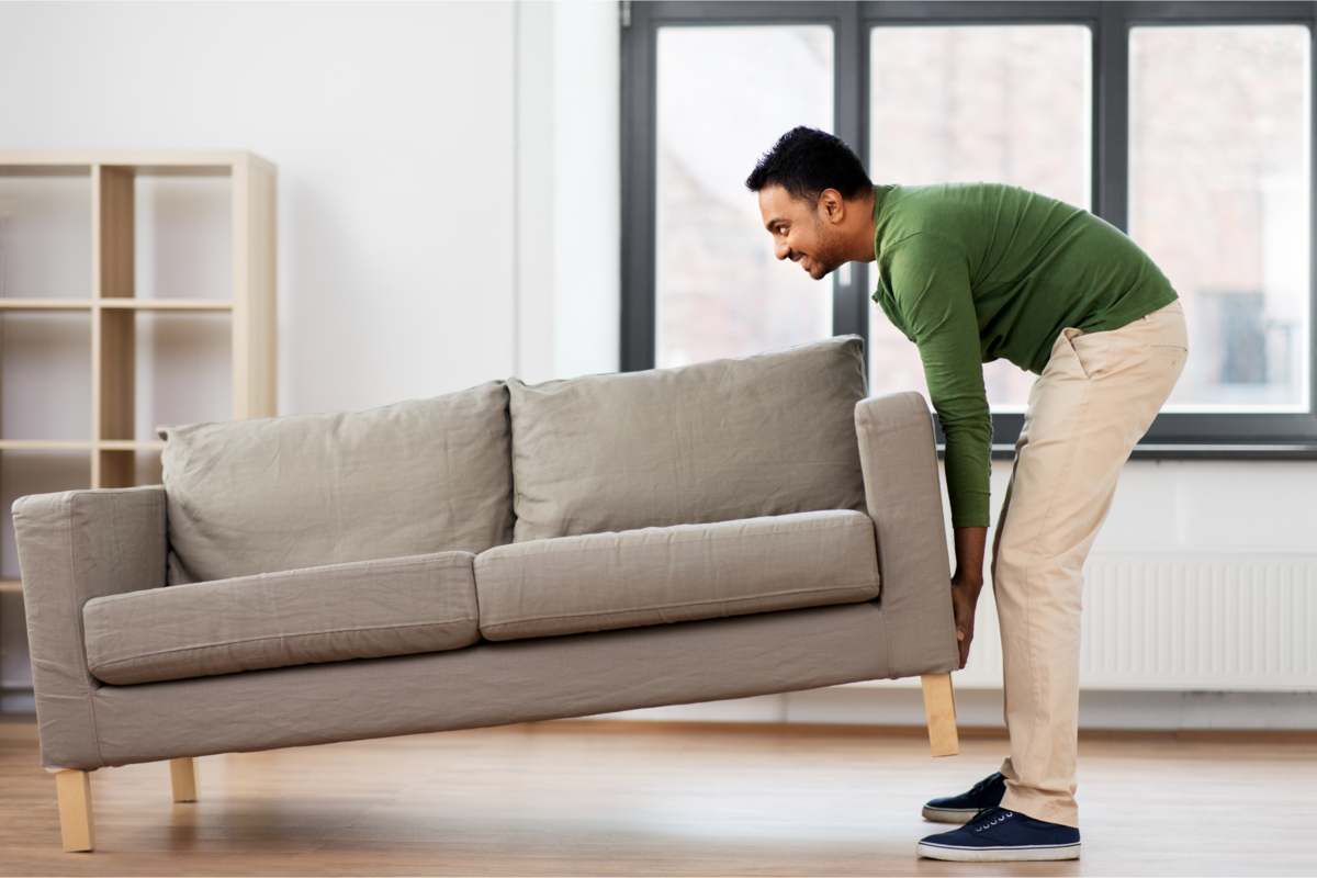 Um homem mudando o sofá de lugar