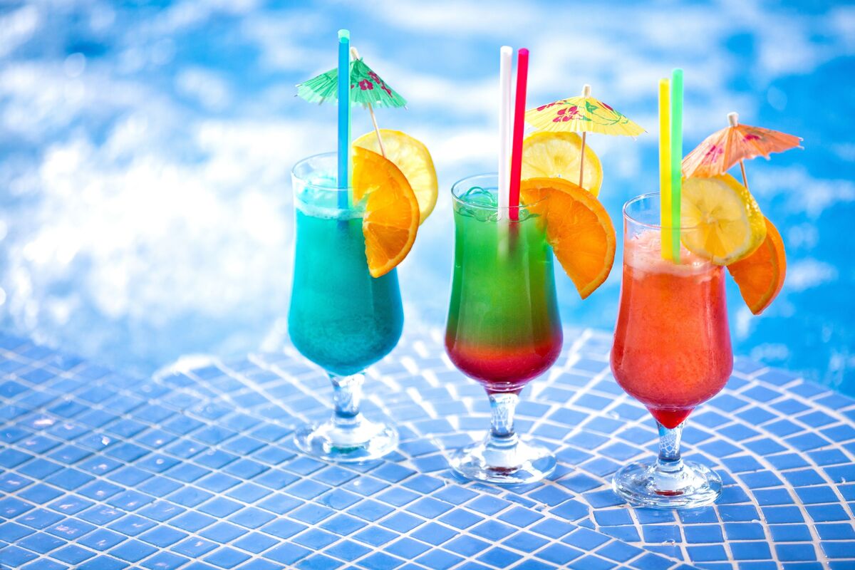 Taças com drinks coloridos na beira da piscina