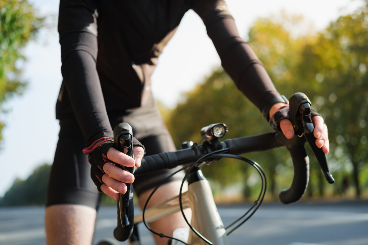 Uma pessoa com roupas de treino pedalando na pista e segurando o guidão de bicicleta aero