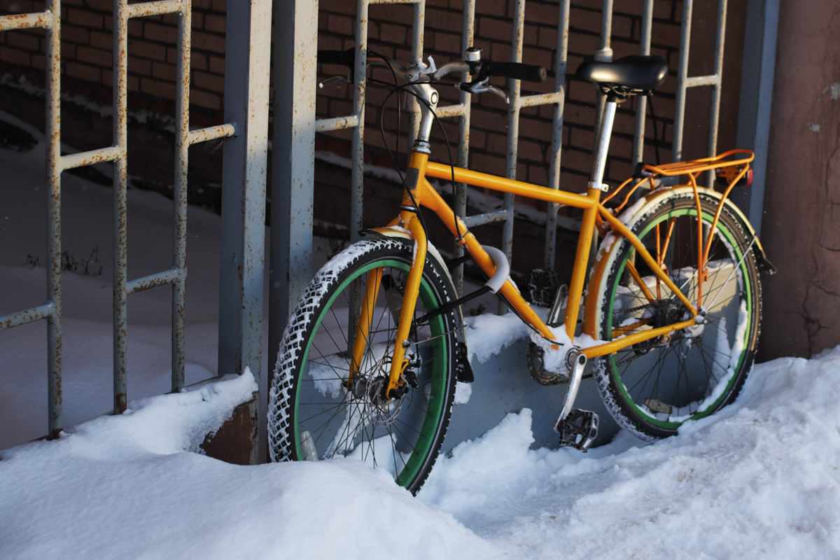 Bicicleta upright amarela estacionada em um local com neve