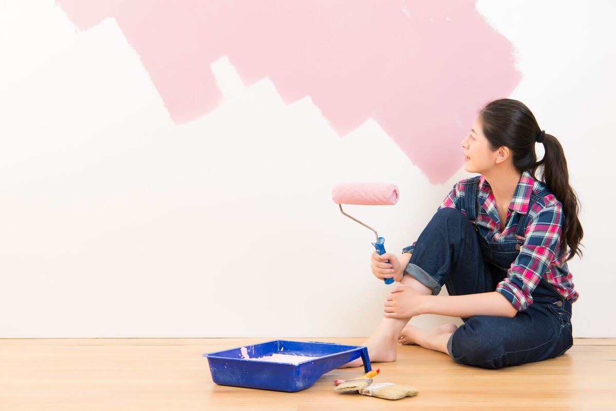 Mulher pintando e admirando parede 