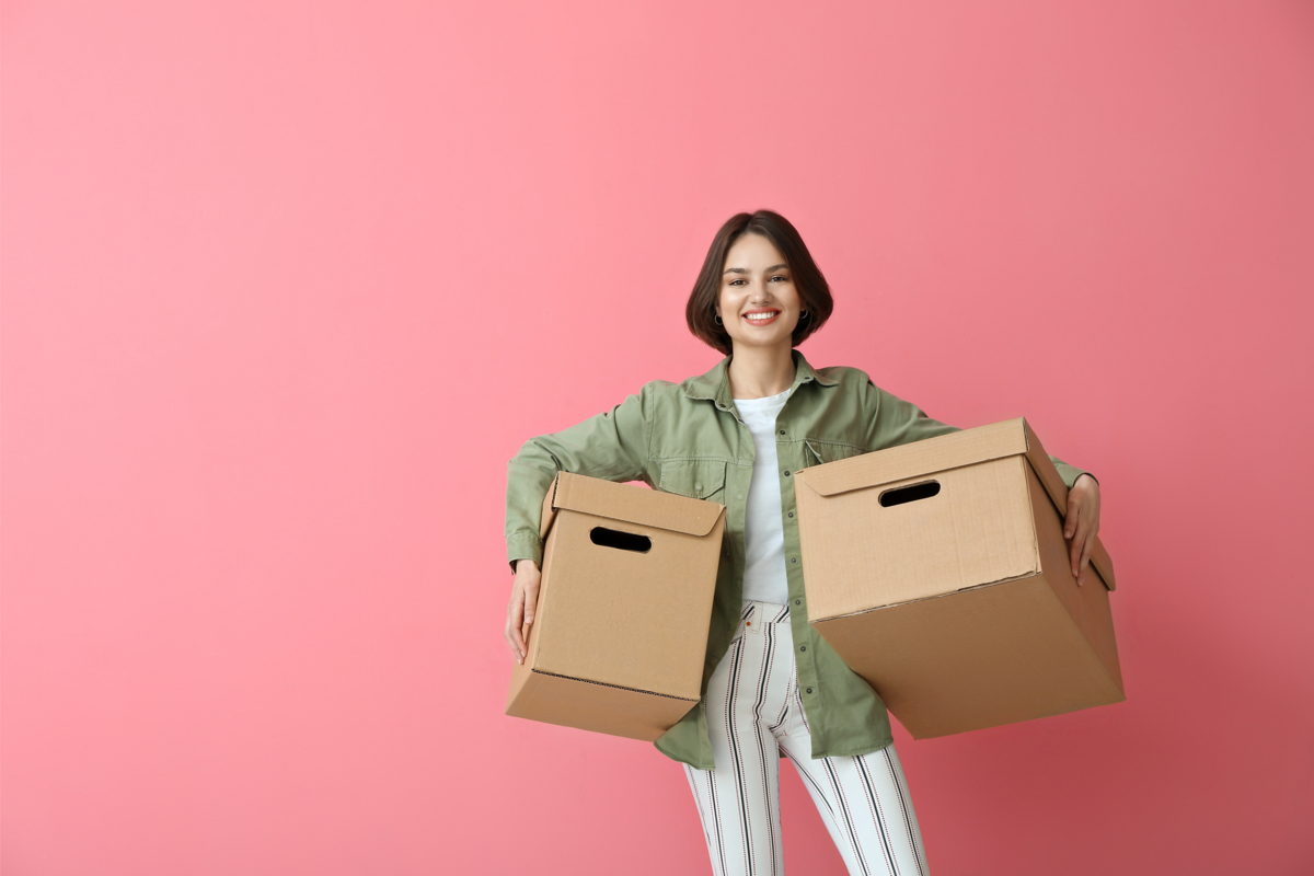 Mulher segurando duas caixas para armazenar calçados, em um fundo rosa.
