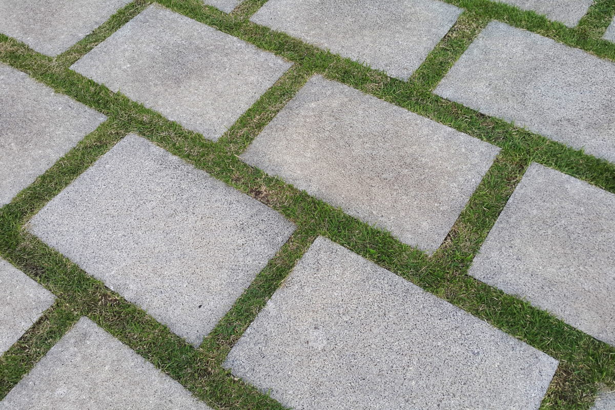 Calçada com blocos intervalados com detalhes de grama.