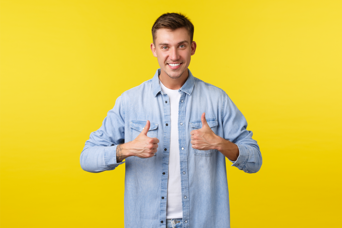 Homem sorrindo com polegar para cima e fundo amarelo