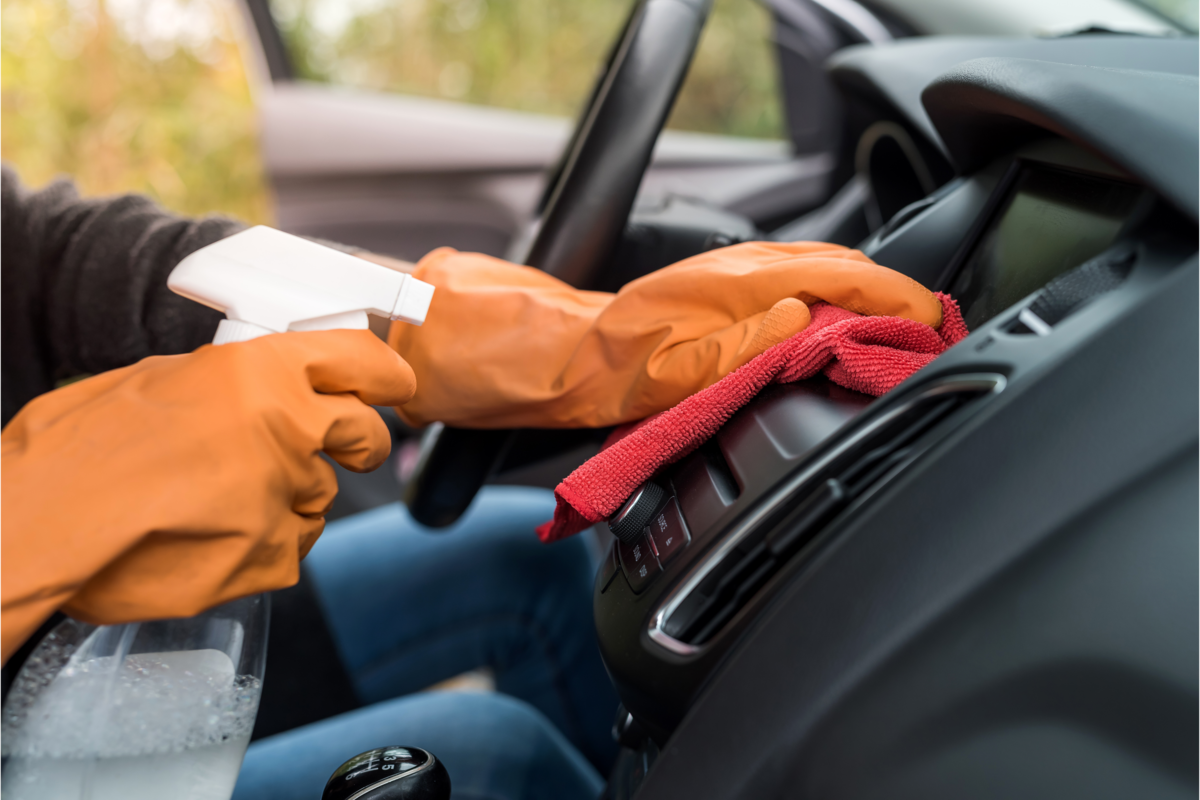 Mão com luvas de proteção fazendo a limpeza do interior do carro