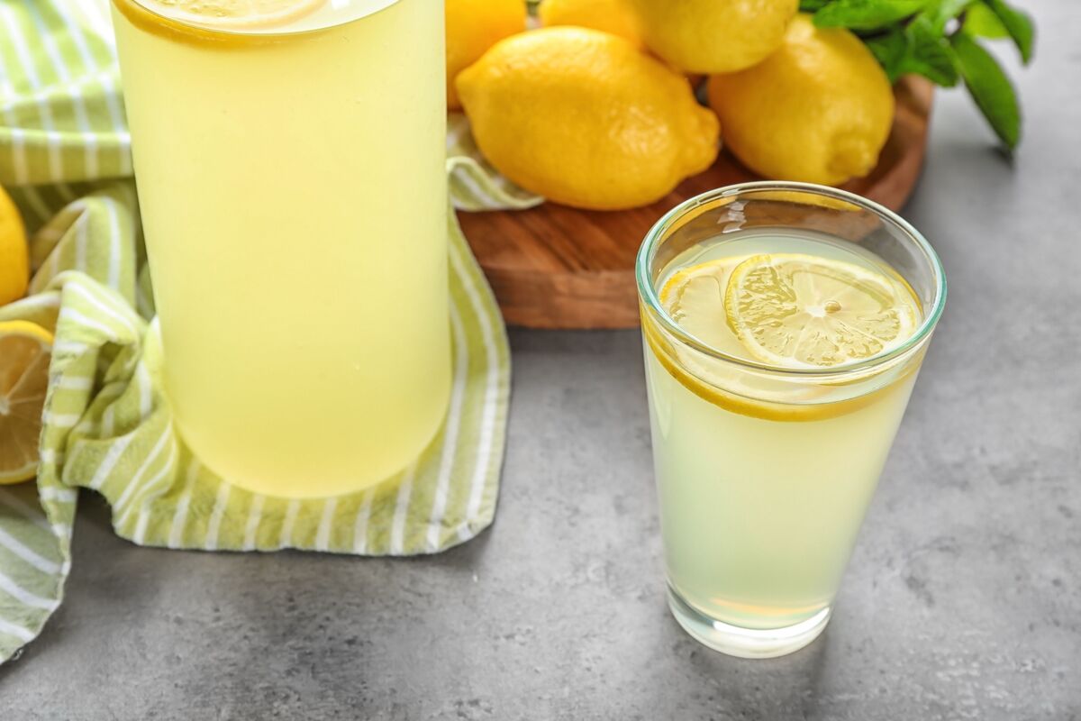 Copo de suco de limão com limões frescos na mesa