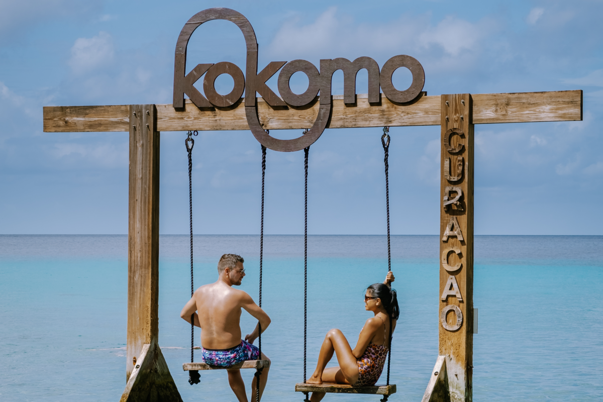 Um casal em balanços que estão presos em uma estrutura escrita Kokomo