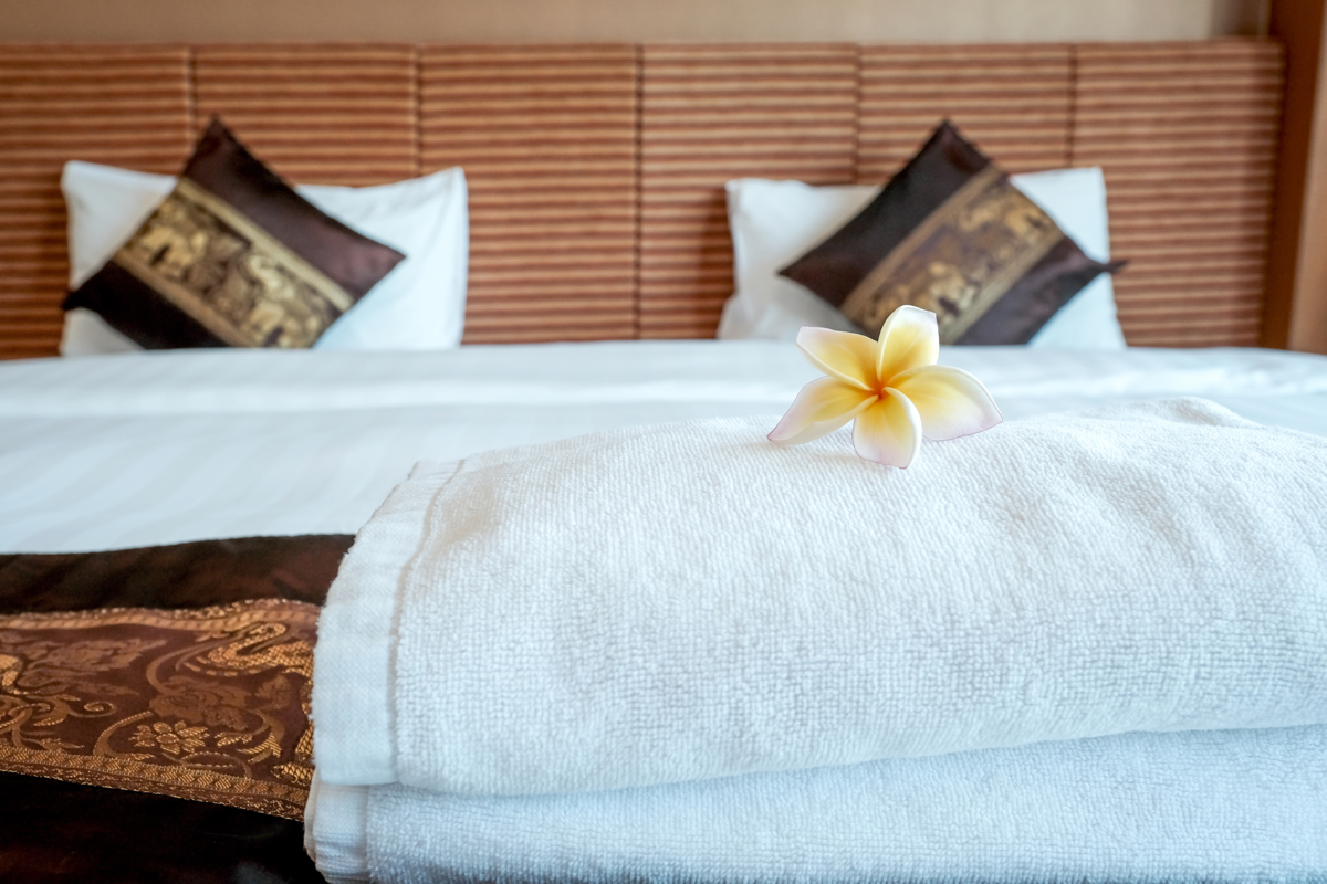 Plumeria e toalhas na cama em quarto de hotel