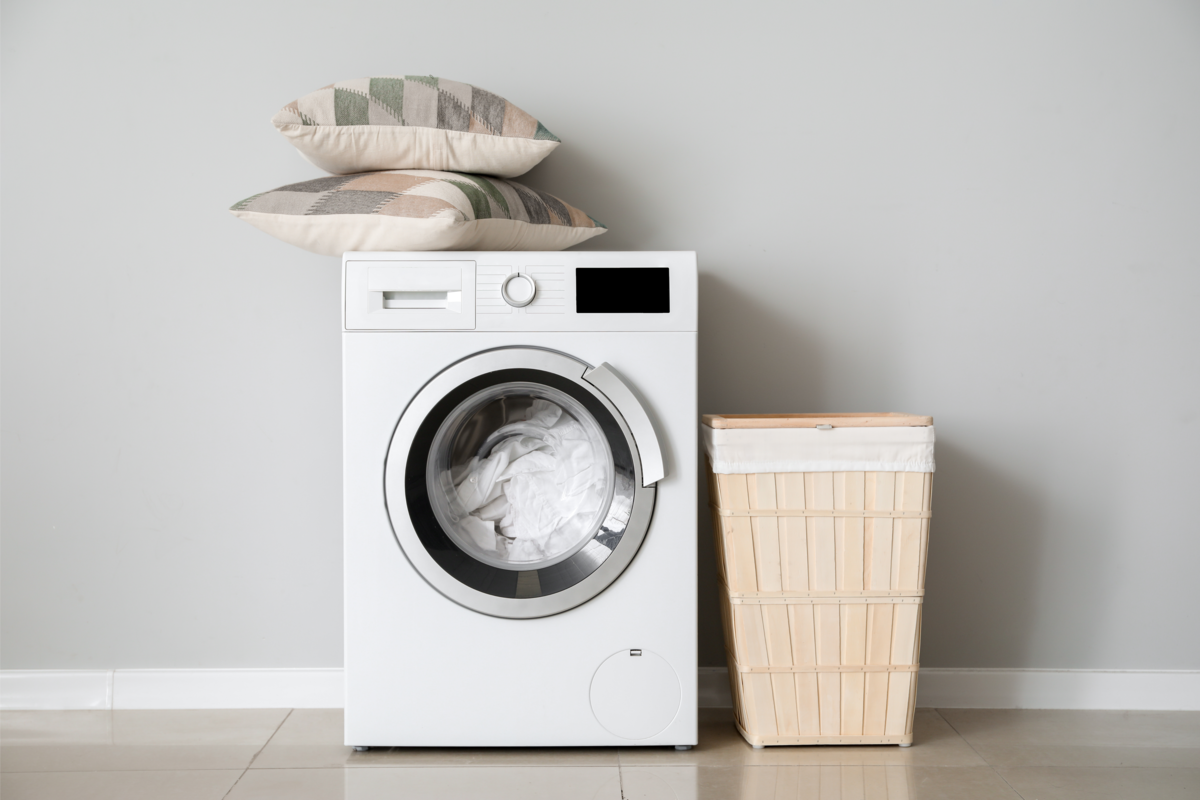 Máquina de lavar roupa moderna na lavanderia perto da parede branca.