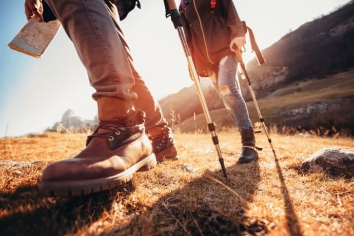 Homem e mulher caminhando com botas de trekking na trilha