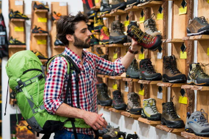 Um homem em uma loja comprando botas para trilha 