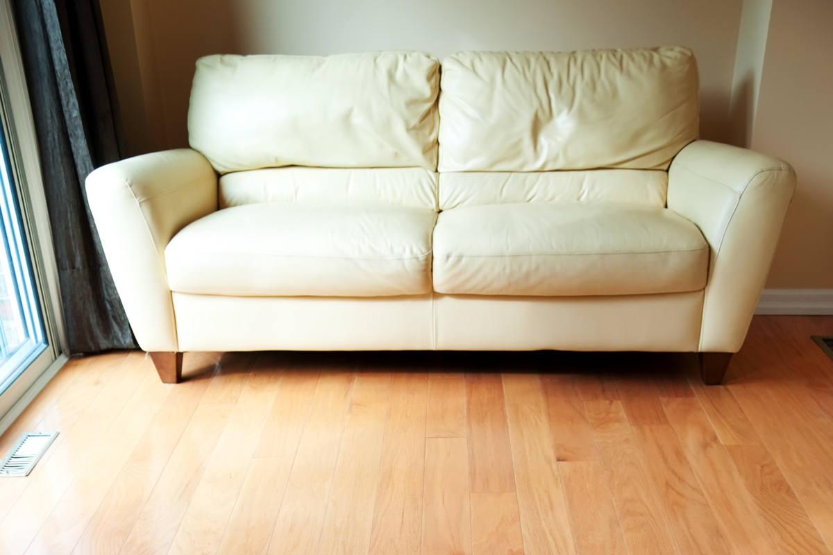 Uma sala com um sofá e piso de madeira taco