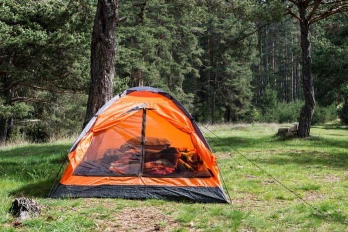 Uma barraca de camping cinza e laranja em uma floresta 