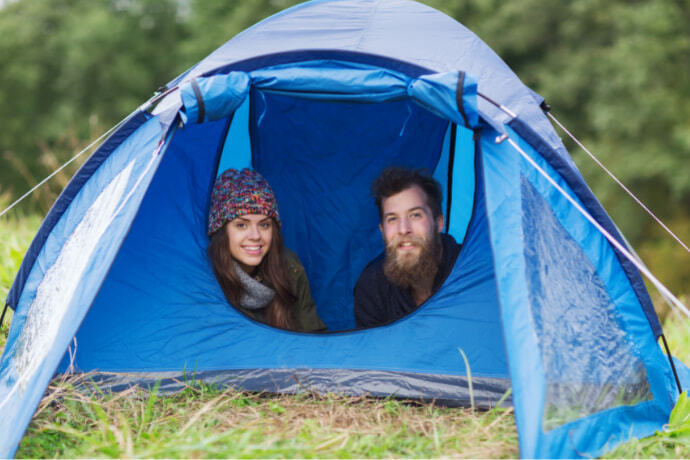 Um casal dentro de uma barraca azul no gramado