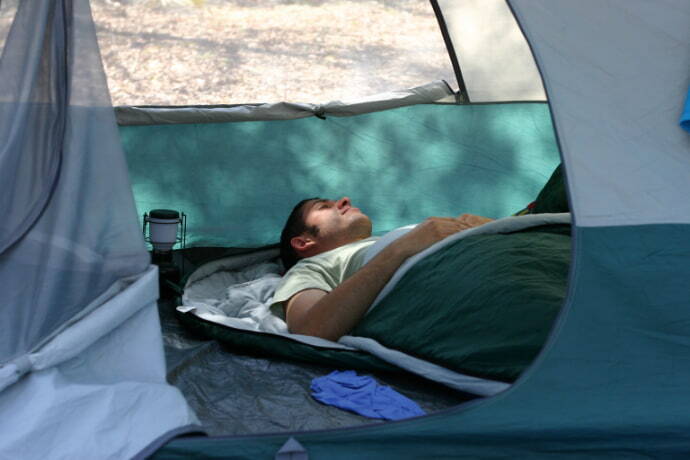 Homem dormindo em uma barraca 