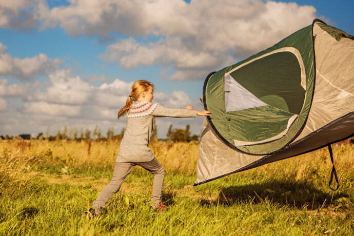 Criança perseguindo uma barraca pega pelo vento em um acampamento de férias