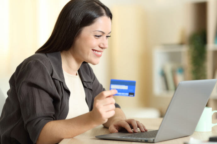 Mulher sorridente, comprando online com cartão de crédito.