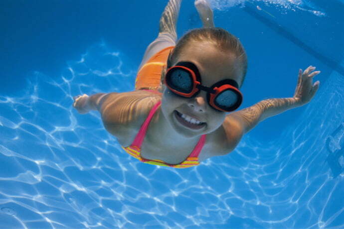 Criança mergulhando na piscina com óculos de natação