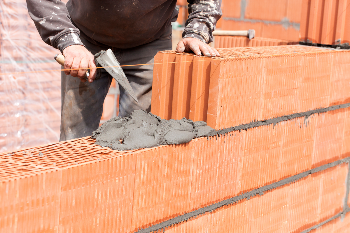 Pedreiro movendo tijolos e construindo paredes de tijolos no canteiro de obras.