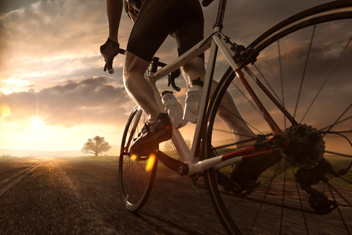 Um ciclista andando de bicicleta e o foco nas rodas e aro da bicicleta 
