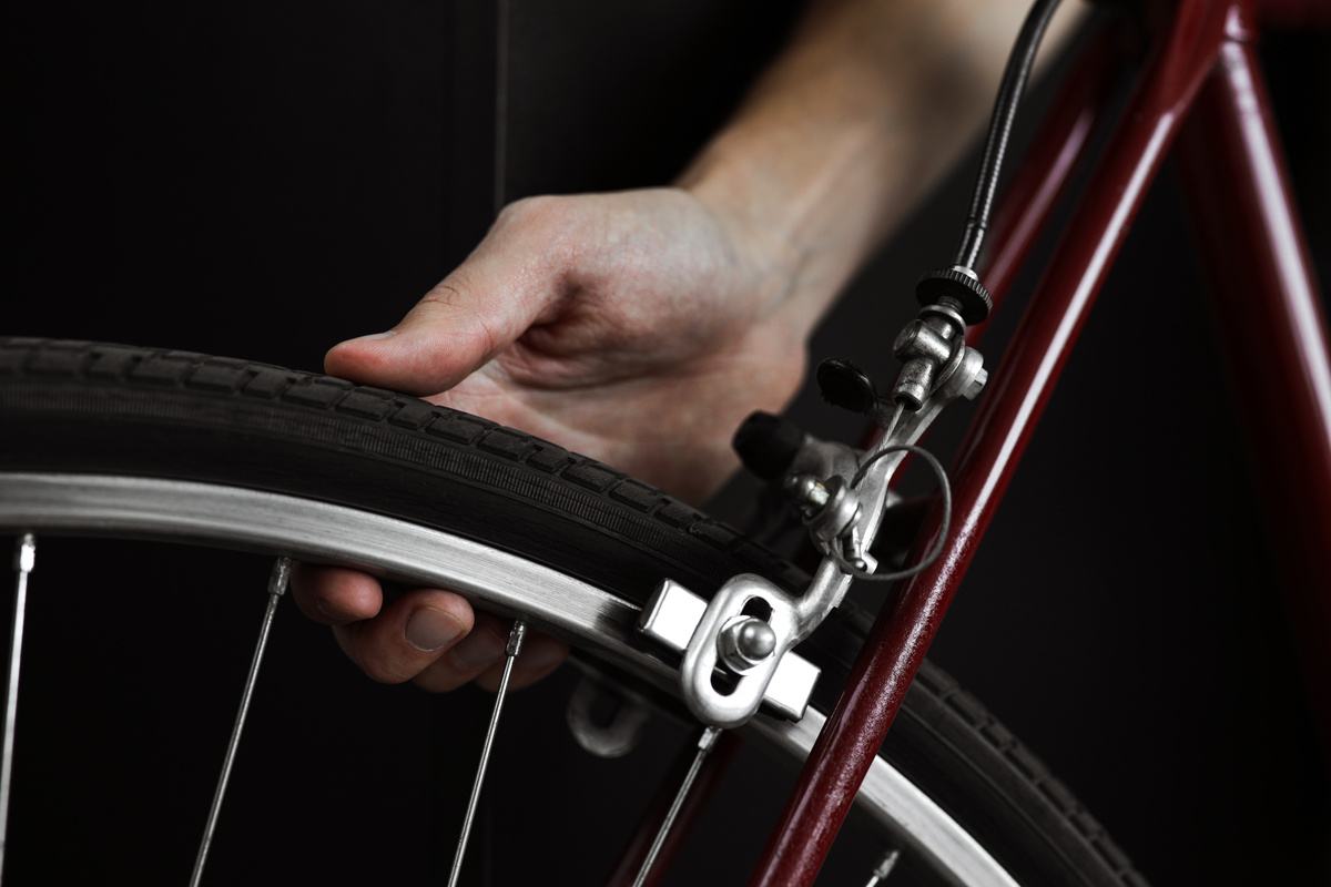 Um homem verificando a pressão nas rodas de uma bicicleta