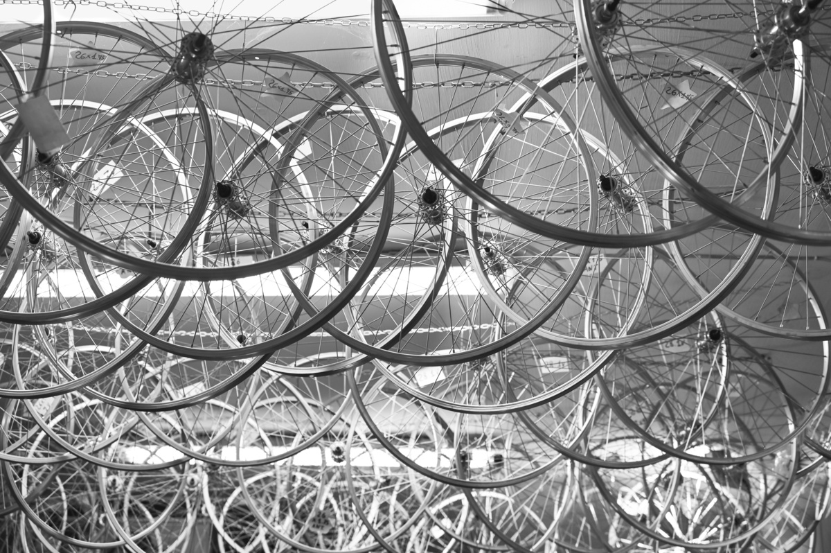 Um grande número de rodas de bicicleta com aros de alumínios pendurados no teto