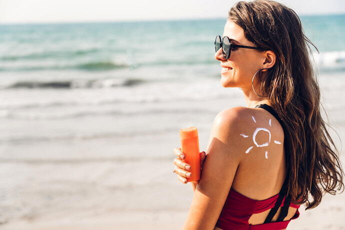 Mulher com protetor solar na praia