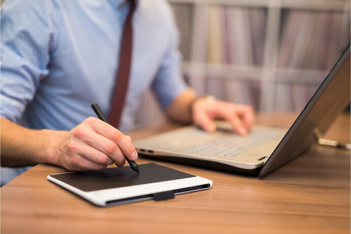 Um homem usando mesa digitalizadora e um notebook