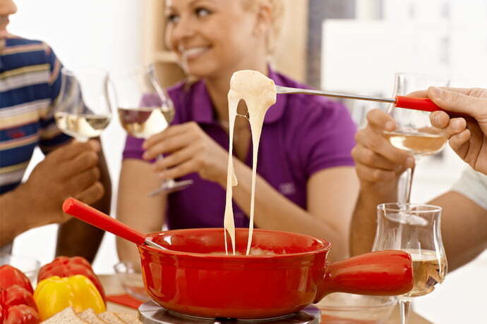 Grupo de amigos desfrutando de um fondue de queijo.