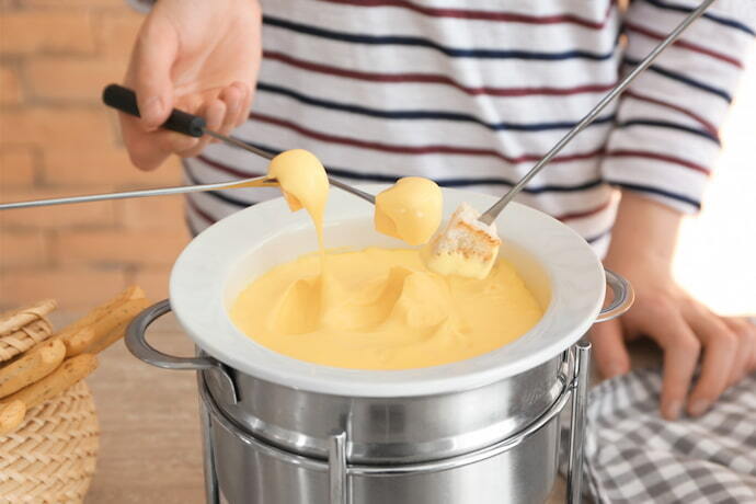 Indivíduo de blusa listrada degustando o fondue de queijo.