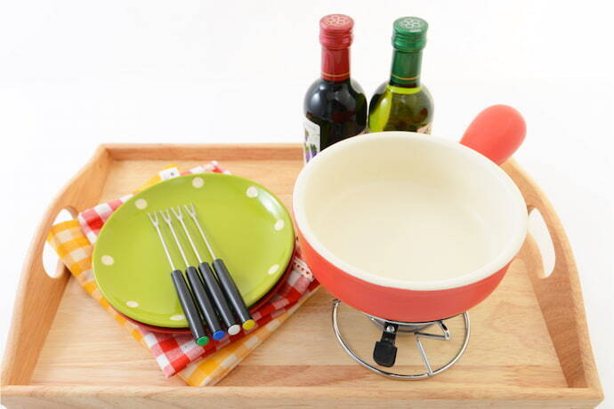 Equipamentos de fondue com garfos e pratos , sobre uma bandeja.