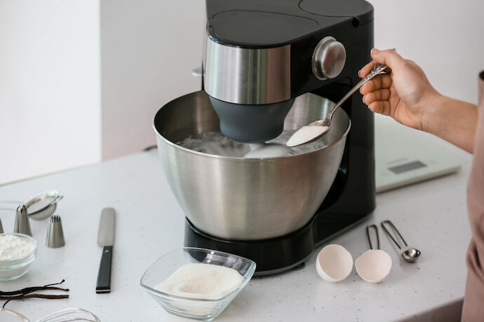  Mulher preparando merengue na cozinha com a batedeira.