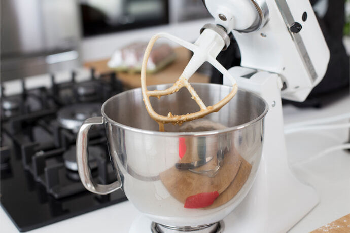 Batedeira orbital de cor branca preparando uma massa de bolo em uma cozinha.