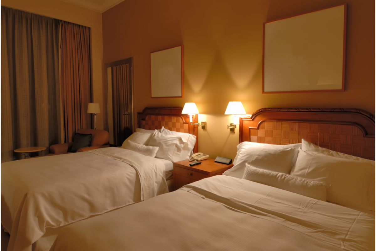Um quarto de hotel com duas camas com lençóis brancos 