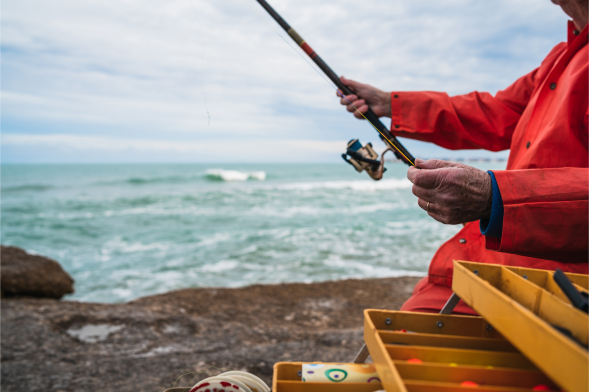 Pescador com caixa de equipamentos de pesca.