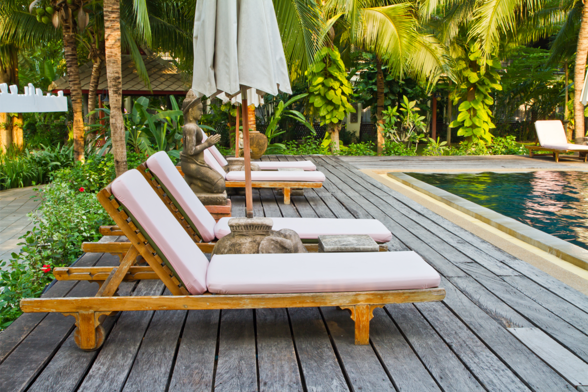 Cadeiras de madeira para spa no deck da piscina e árvores ao redor. 