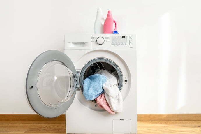 Máquina de lavar roupa moderna com a porta aberta e cheia de roupa.