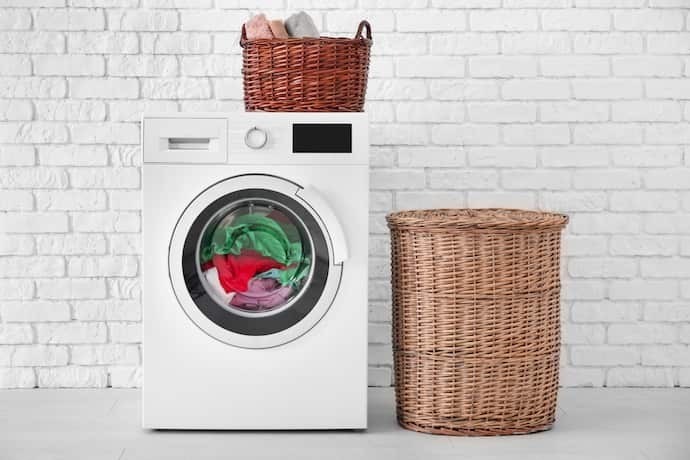 Máquina de lavar na lavanderia com parede de tijolos de cor branca.