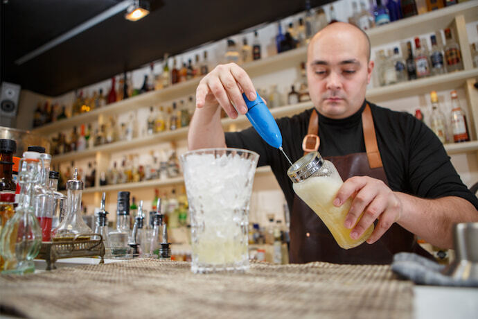 Barman usando um mixer manual para preparar uma bebida em um bar ou pub.