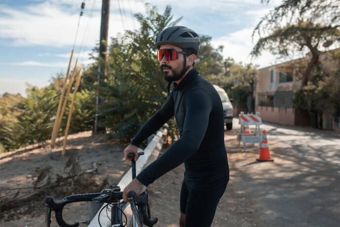 Homem de camisa preta de manga comprida e bermuda andando de bicicleta