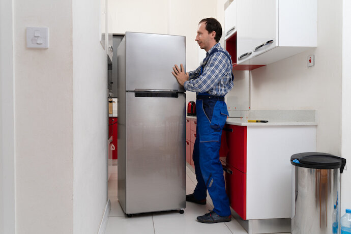 Homem instalando a geladeira pequena de aço inox.