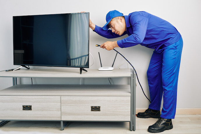 Homem de roupa azul instalando uma Smart TV.