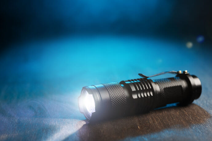 Close-up de uma lanterna tática em um fundo escuro.
