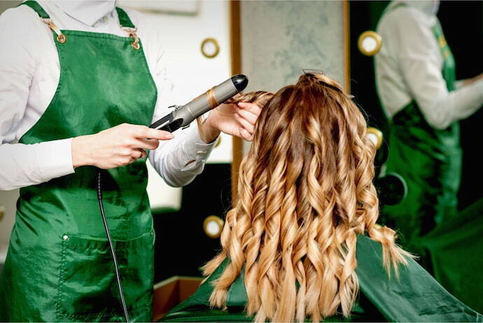 Profissional fazendo ondulações em cabelo de mulher no salão 