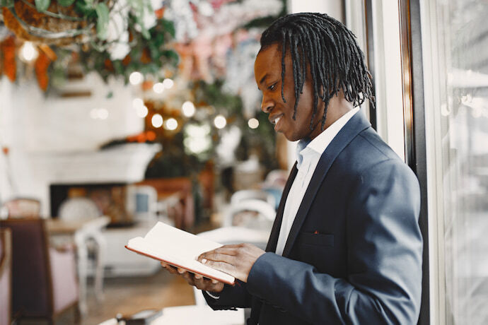 Homem de negócios sorridente lendo um livro dentro da cafeteria.